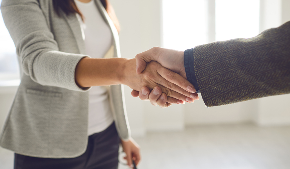 Two individuals wearing suits shaking hands.