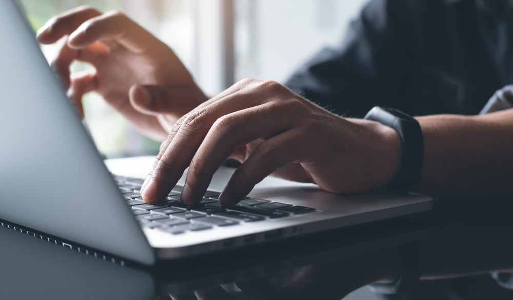 Individual typing on a laptop.